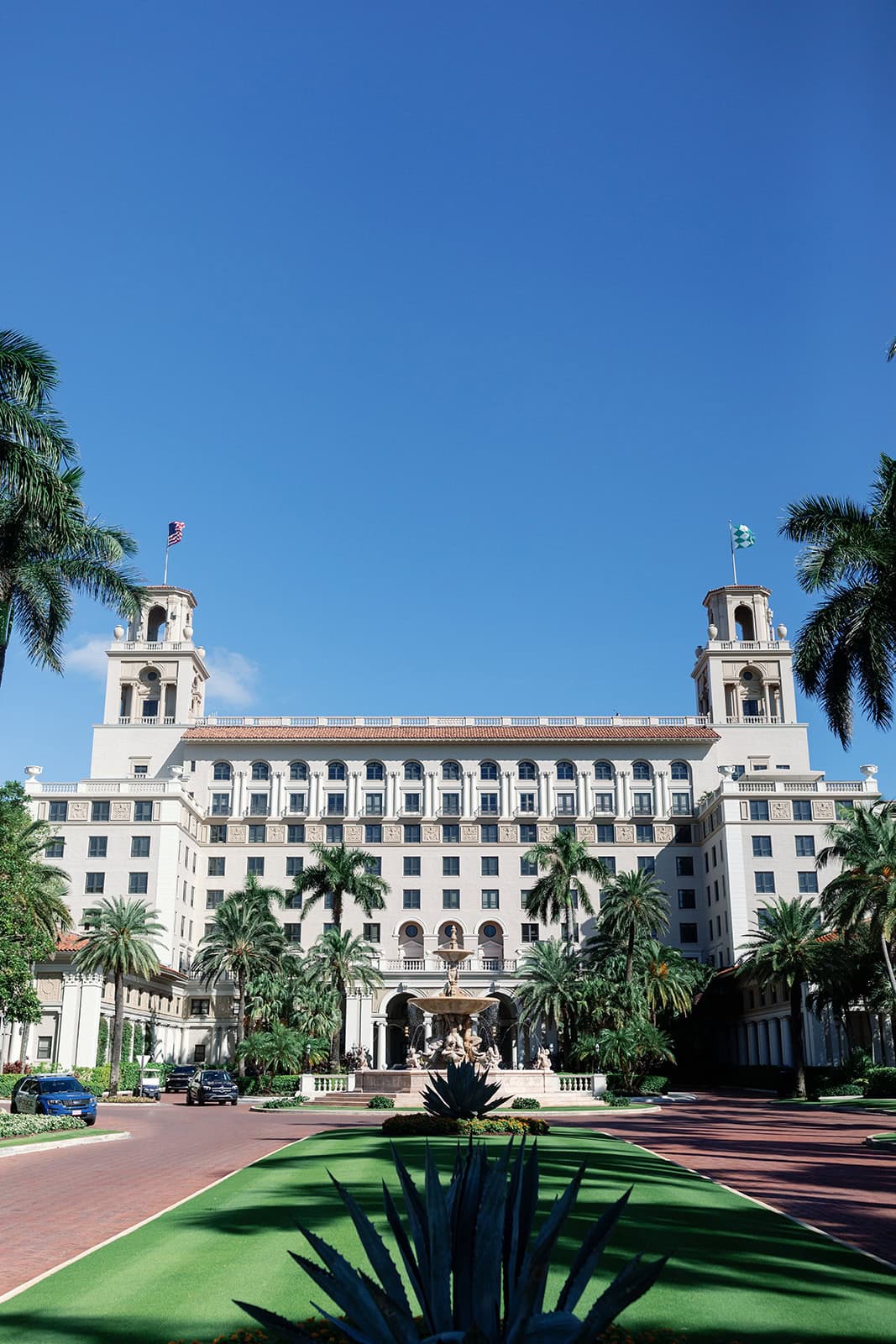 Front building of The Breakers in Palm Beach with palm tress in the foreground. 